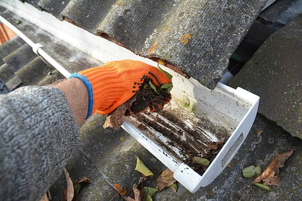 Rain Gutter Cleaning from Leaves in Autumn with hand. Roof Gutter Cleaning Tips. Clean Your Gutters Before They Clean Out Your Wallet. Step by Step. Gutter Cleaning. - Denver Gutter Cleaning